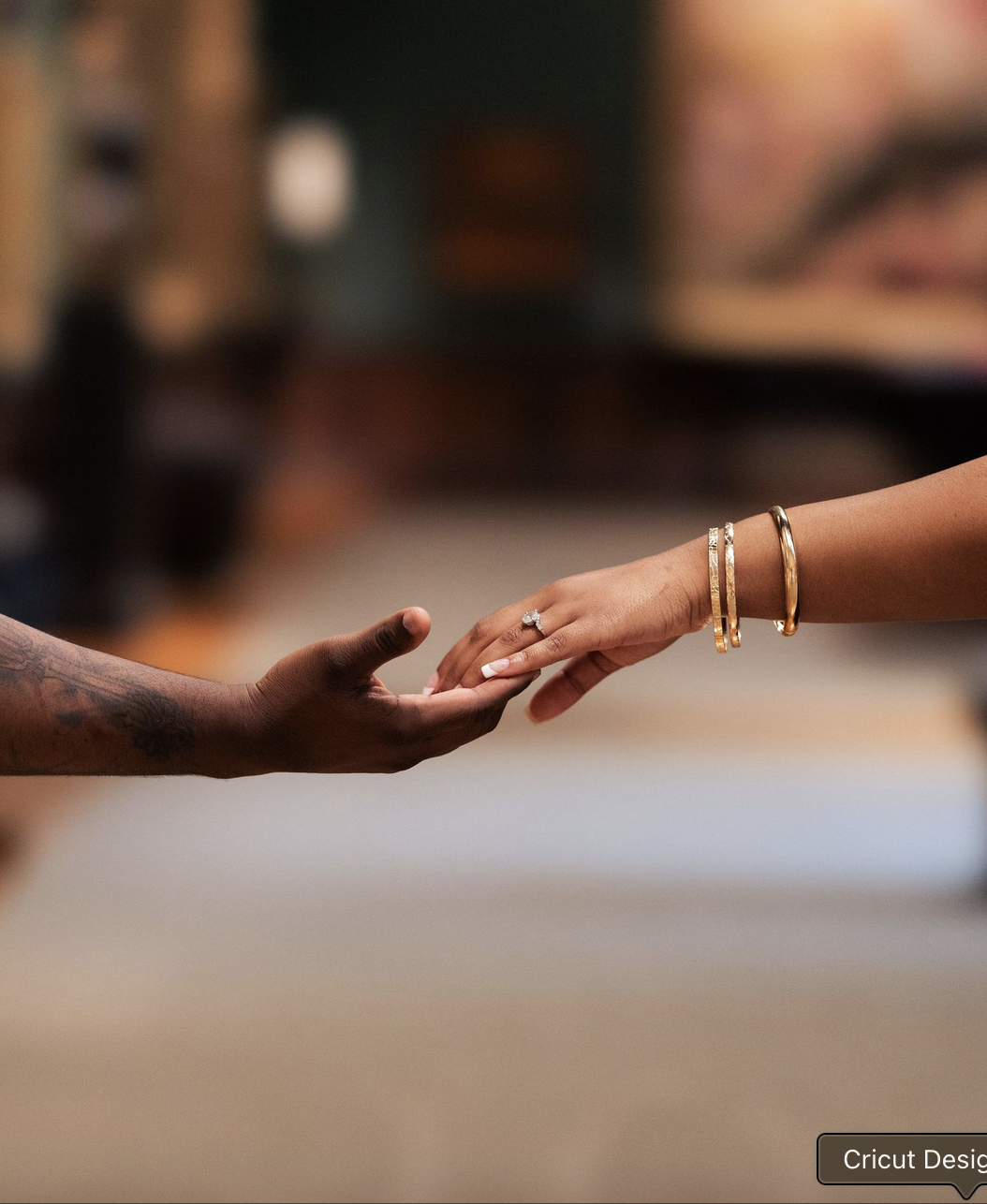 Close-up of a couple reaching for each other's hands, showing an engagement ring