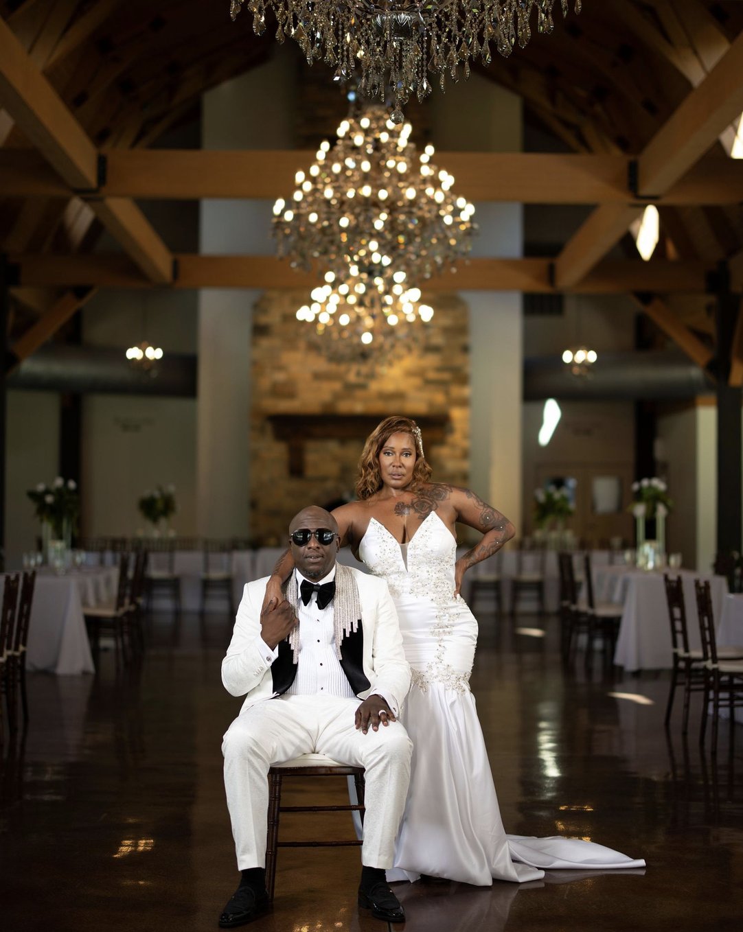 Bride and groom posed together under a chandelier at their reception