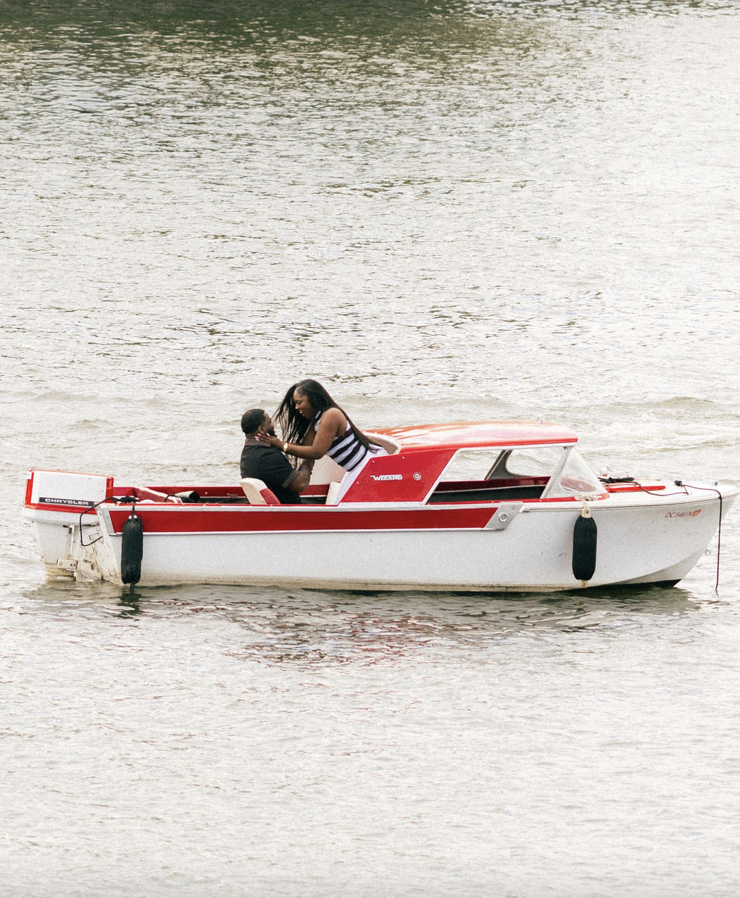 Couple embracing on a red and white boat on the water